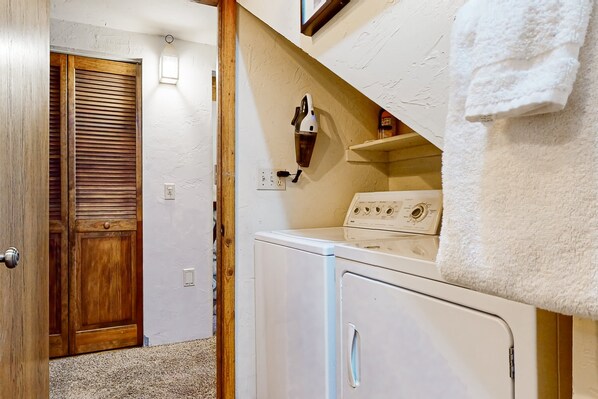 A laundry room with a washing machine, a dryer, and a wooden door. - Spacious dog-friendly cabin with creek & mountain views (Idyllwild)