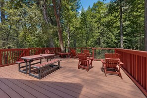 Une terrasse extérieure avec des rampes rouges, des tables en bois et des chaises Adirondack.