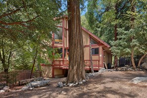 A two-story cabin with a balcony, surrounded by trees and a natural landscape. - Spacious dog-friendly cabin with creek & mountain views (Idyllwild)