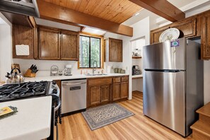 Une cuisine moderne avec des meubles en bois, des appareils électroménagers en acier inoxydable et une grande fenêtre qui laisse entrer la lumière naturelle.