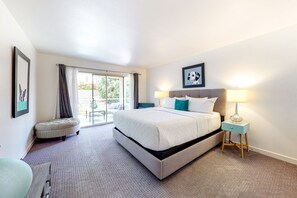 A hotel room with a large bed, a small stool, a nightstand with a lamp, and a picture on the wall. - Upscale Home in Classy Indian Wells (Indian Wells)