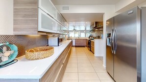 Eine moderne Küche mit einem Edelstahl-Kühlschrank, weißen Schränken und einem gefliesten Boden.
