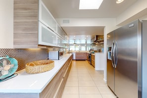 A modern kitchen with a stainless steel refrigerator, white cabinets, and a tiled floor. - Upscale Home in Classy Indian Wells (Indian Wells)