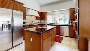 Uma cozinha moderna com armários de madeira, eletrodomésticos de aço inoxidável, uma ilha grande e uma janela com vista para o exterior.