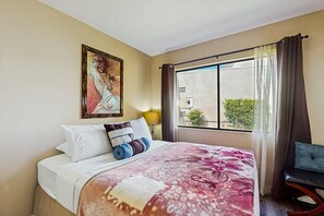 A hotel room with a bed, a chair, a window with curtains, and a painting on the wall. - Ground-floor, golf-adjacent getaway w/ free WiFi, central A/C, & 20 shared pools (Palm Desert)