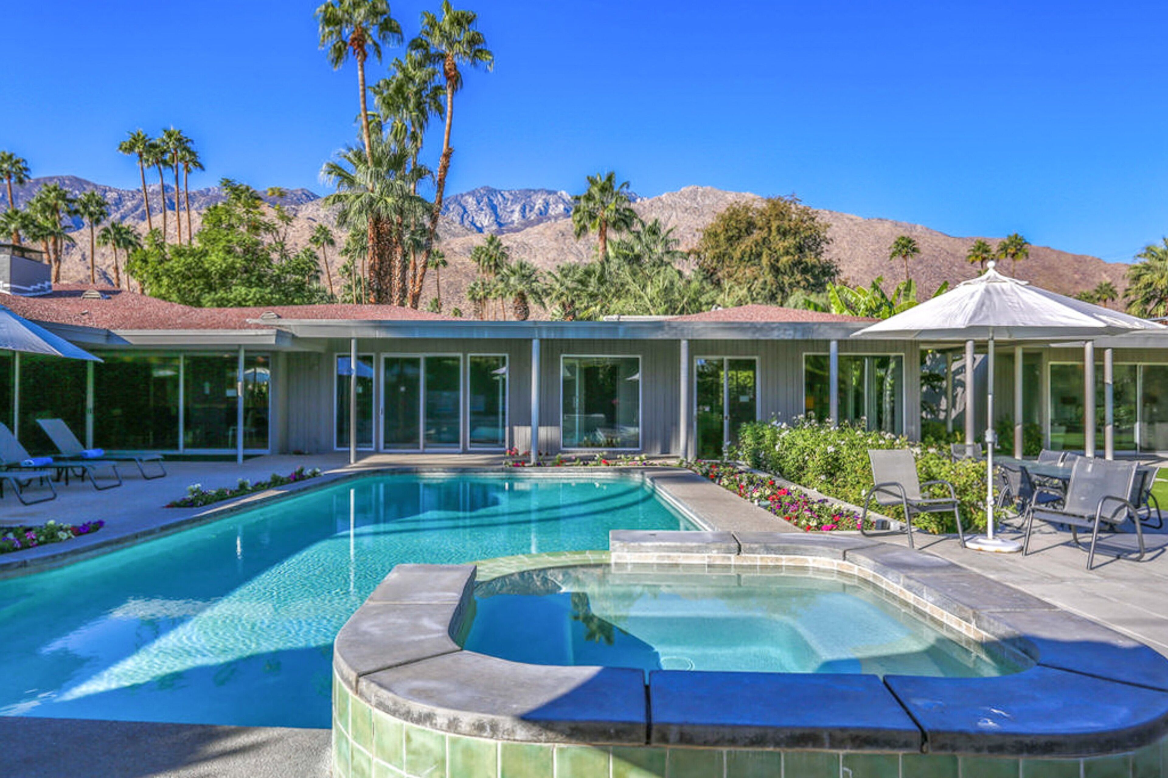 A swimming pool with a hot tub, lounge chairs, and a covered seating area.