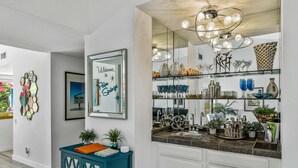 Una cocina moderna con una isla grande, horno empotrado y varios objetos decorativos en los estantes.