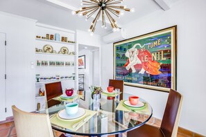 Un coin repas avec une table en verre, des chaises et une affiche accrochée au mur.