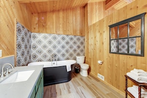 A bathroom with a wooden interior, a bathtub, a sink, and a toilet.