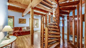 A wooden spiral staircase in a room with a wooden floor, a sofa, and a lamp.