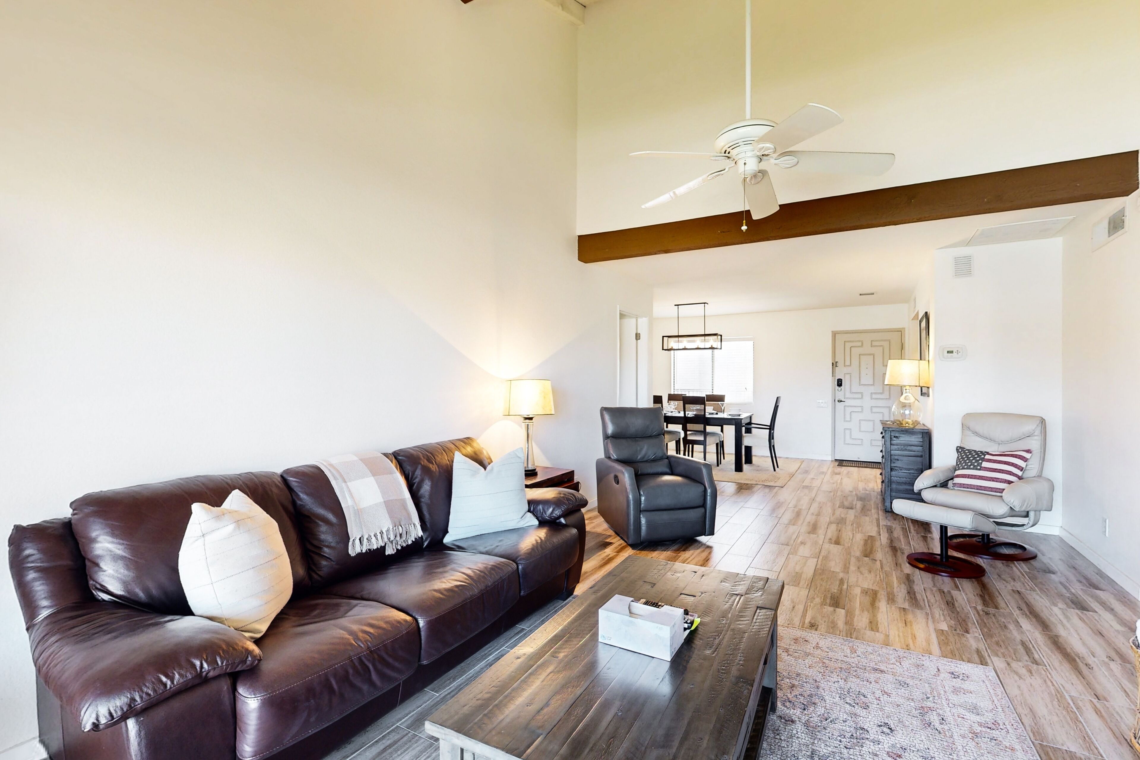 A modern living room with a leather sofa, a coffee table, and a ceiling fan.