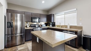 A modern kitchen with stainless steel appliances, dark cabinetry, and a granite countertop island.