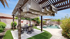 A patio area with a pool, outdoor furniture, and a pergola structure.