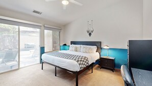 A bedroom with a bed, a nightstand, a desk, and a chair.