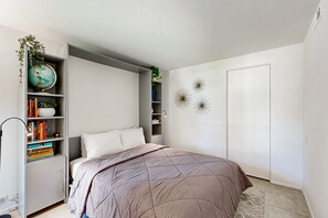 A bedroom with a bed, a bookshelf, a globe, and decorative wall art. - Updated Mid-Century Gem | 3 Patios & Gas Grill | Near Downtown (Palm Springs)