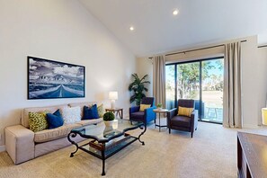 A modern living room with a sofa, armchairs, a coffee table, and a large window with curtains. - Golfers Delight Lake-View Condo on PGA West Course - Pool & Spa (La Quinta)