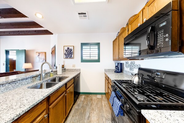 A kitchen with granite countertops, wooden cabinets, a stove, and a microwave.