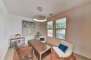 Ein modernes Wohnzimmer mit einem Glastisch, einem weißen Sofa und einem großen abstrakten Gemälde.