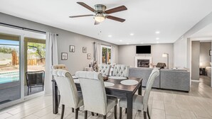 A modern kitchen with a central island, a dining area with a round table and chairs, and a pool visible through the glass doors. - Dog-friendly sunshine stay with private pool, spacious yard, central AC & W/D (Tucson)