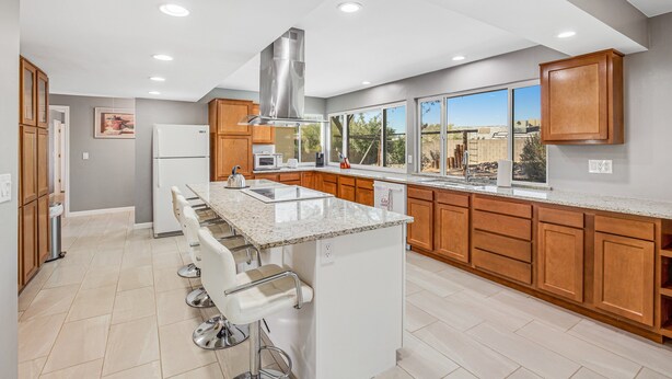 A modern kitchen with a central island, wooden cabinets, and a large window providing a view. - Dog-friendly sunshine stay with private pool, spacious yard, central AC & W/D (Tucson)