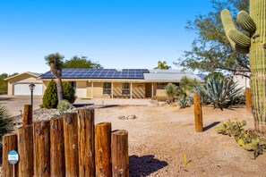 A house with solar panels, a wooden fence, and desert vegetation. - Dog-friendly sunshine stay with private pool, spacious yard, central AC & W/D (Tucson)