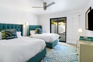 Un dormitorio moderno con dos camas, un ventilador de techo y vistas al exterior.