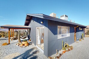 Ein modernes Haus mit Satteldach, großen Fenstern und einer Auffahrt mit Kies.