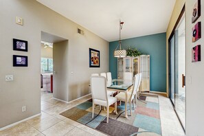 A dining area with a glass table, white chairs, a patterned rug, and a ceiling fan. - Spacious All-Suite Resort Condo at PGA West with Patio & Pool 2BR #065256 (La Quinta)