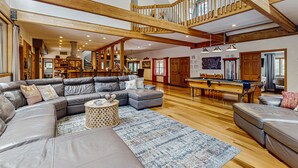 A spacious living area with a large sectional sofa, a pool table, and a wooden staircase. - Stunning Fern Valley cabin with forest views & private hot tub - dog-friendly (Idyllwild)