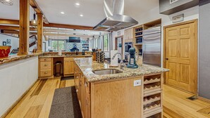 A spacious kitchen with granite countertops, wooden cabinets, a stainless steel range hood, and built-in wine racks. - Stunning Fern Valley cabin with forest views & private hot tub - dog-friendly (Idyllwild)
