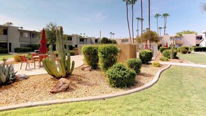 A landscaped garden with cacti and palm trees, outdoor seating, and a building with multiple balconies. - Welcoming condo with WiFi & pool - near Scottsdale Fashion Square (Scottsdale)