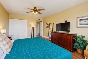 A bedroom with a bed, a dresser, a television, a ceiling fan, and a door leading to another room. - Welcoming condo with WiFi & pool - near Scottsdale Fashion Square (Scottsdale)
