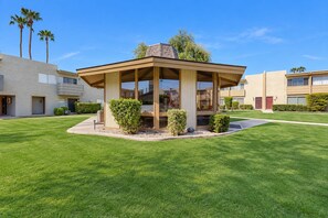 A modern outdoor gazebo with a glass enclosure, surrounded by well-maintained grass and small shrubs. - Welcoming condo with WiFi & pool - near Scottsdale Fashion Square (Scottsdale)