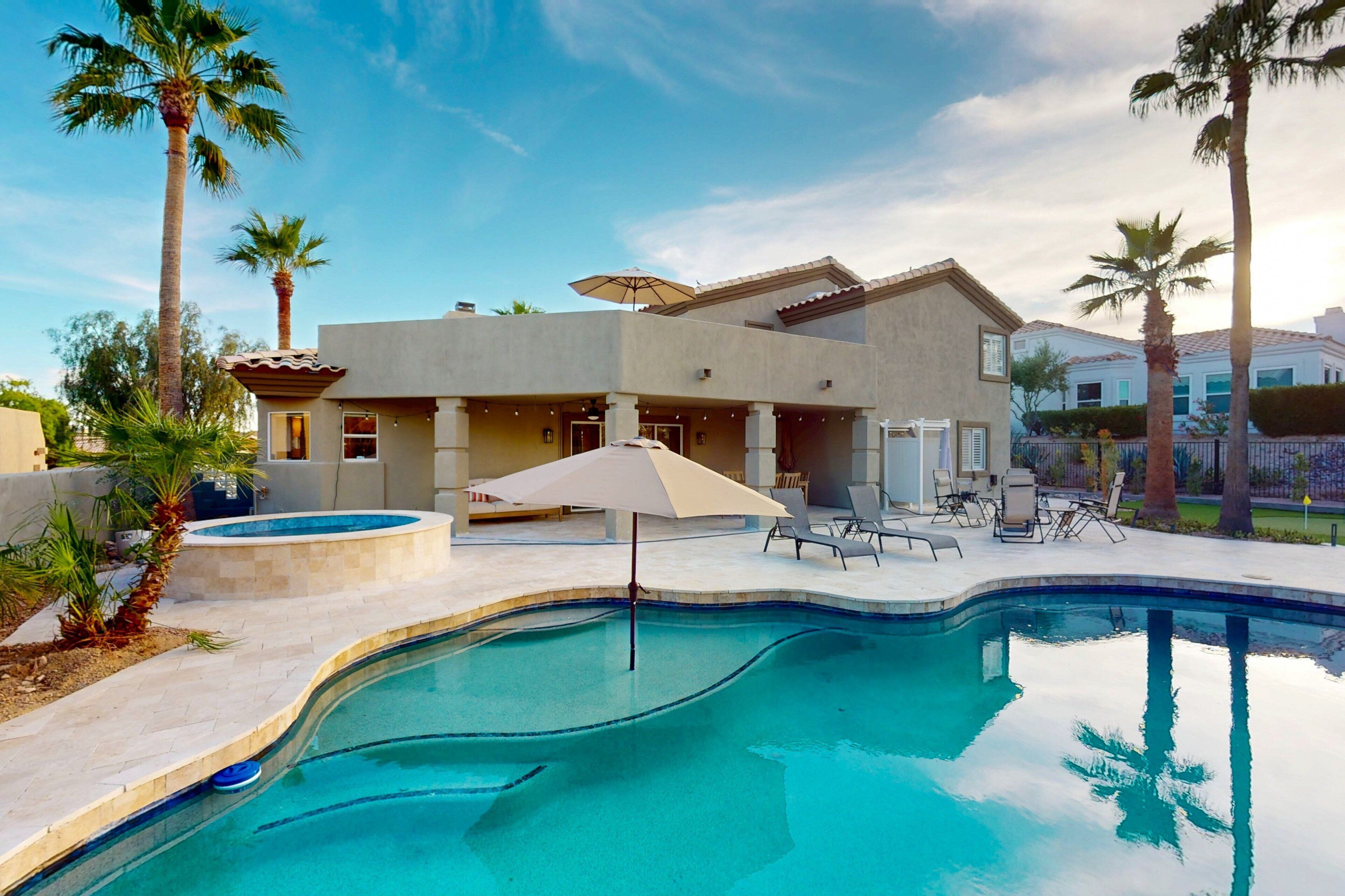 A modern house with a swimming pool, palm trees, and outdoor seating.