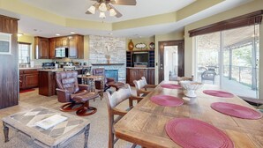 A spacious kitchen with dark wooden cabinets, a stone fireplace, and a dining area with a large wooden table and leather chairs. - Private Casita Overlooking Winery | Grill, Central AC (Temecula)