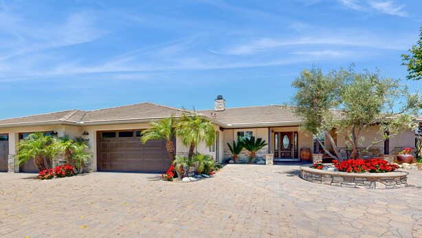 A two-story house with a garage, palm trees, and a stone patio. - Private Casita Overlooking Winery | Grill, Central AC (Temecula)