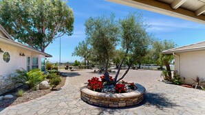 A paved courtyard with a stone planter, trees, and a building with a stone facade. - Private Casita Overlooking Winery | Grill, Central AC (Temecula)