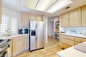 Eine moderne Küche mit Holzausstattung, einem Edelstahlkühlschrank, einer Kaffeemaschine und einem Herd.