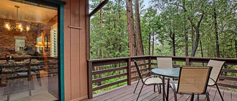A wooden deck with a glass door leading to an interior space, surrounded by a forest.
