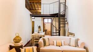 A cozy living room with a sofa, a dining table, and a spiral staircase. - Apartment "Il Campo", in the center of Siena, a few steps from Piazza del Campo (siena)