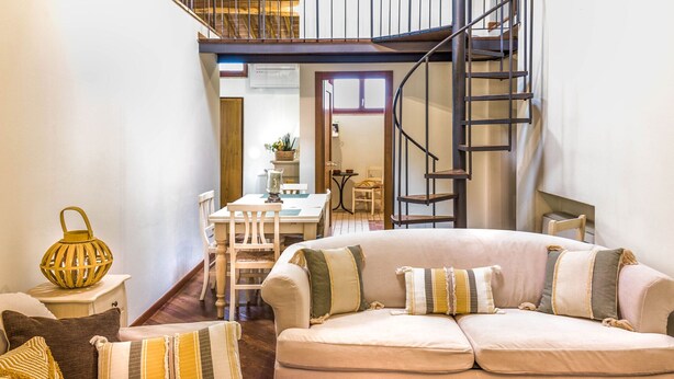 A cozy living room with a sofa, a dining table, chairs, and a staircase. - Apartment "Il Campo", in the center of Siena, a few steps from Piazza del Campo (siena)