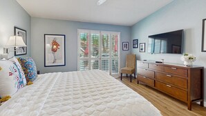 Een slaapkamer met een groot bed, een kaptafel, een stoel en een plafondventilator.