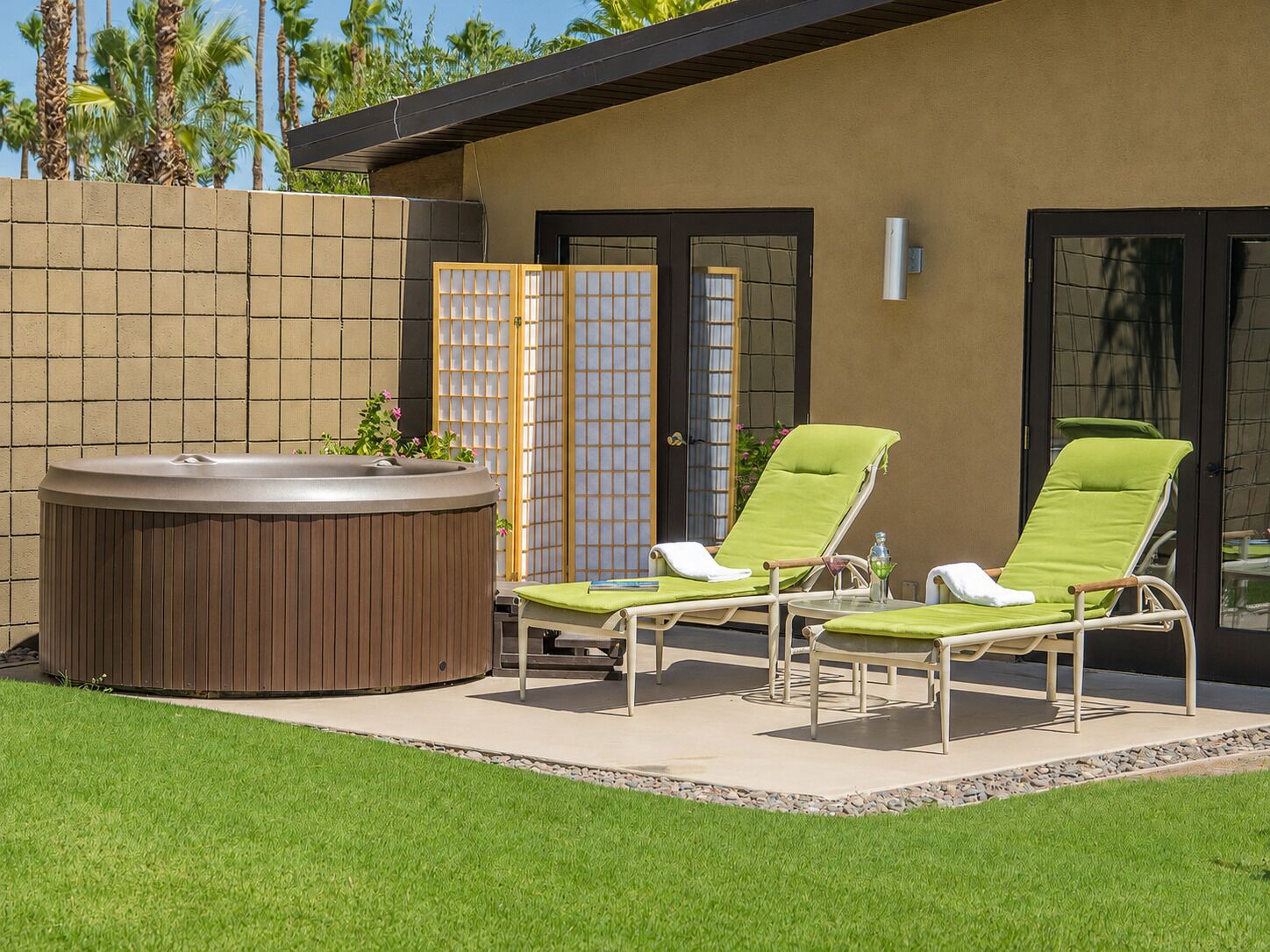 Een hottub met twee loungestoelen en een houten omheining.