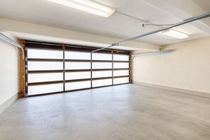 Eine Garage mit großer, offener Tür, Leuchtstofflampen und einem Betonboden.