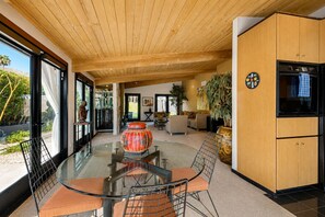 Ein modernes Interieur mit einem Glastisch, Holzboden und einer Küche mit Schränken.