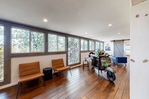 A spacious room with large windows, a wooden floor, and a vintage scooter.