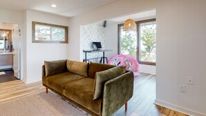 A modern living room with a brown sofa, a small table, and a decorative chair. - Charming home with full kitchen, fireplace, grill, & viewing deck (Idyllwild)