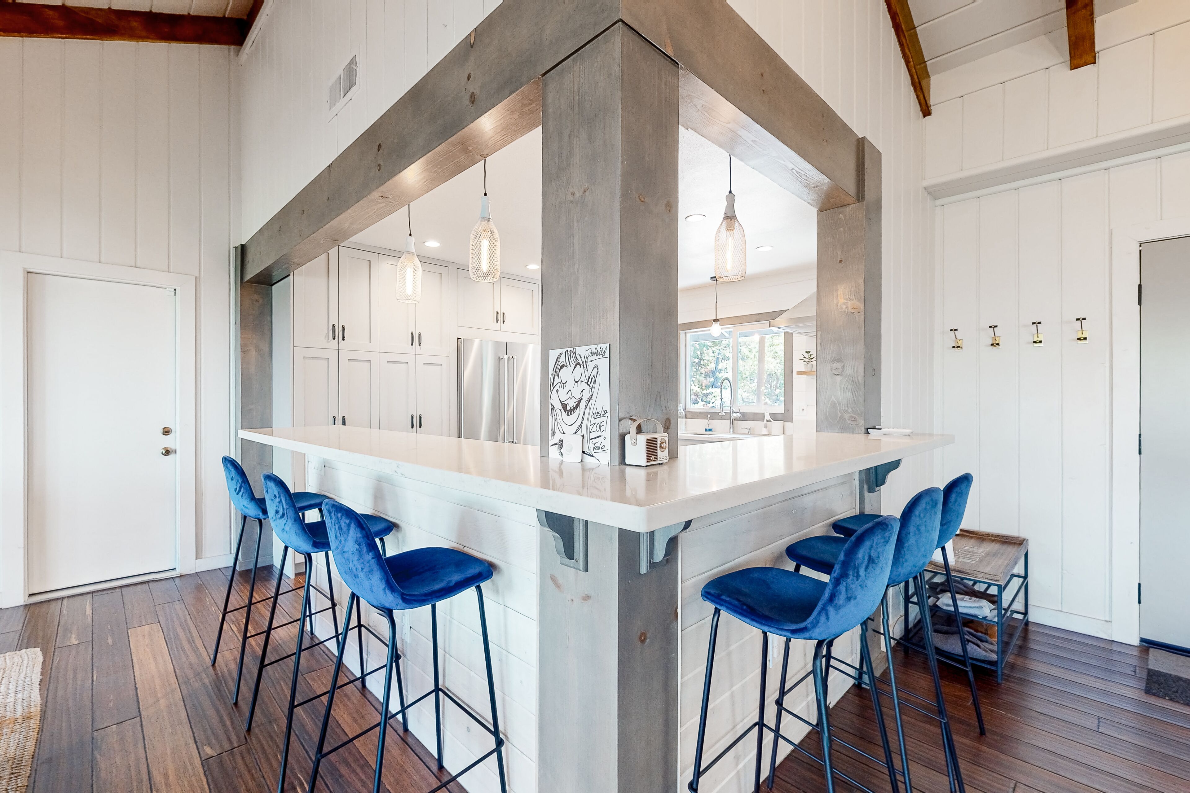 A kitchen with a central island, bar stools, and a view of the outdoors.