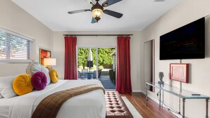 Une chambre à coucher avec un lit, un ventilateur de plafond, une télévision et une vue sur l’extérieur.