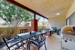 An outdoor patio with a table and chairs, a barbecue grill, and a bamboo fence. - Vibrant dog-friendly condo with hot tub, tennis court, pool, W/D, grill & patio (Palm Springs)